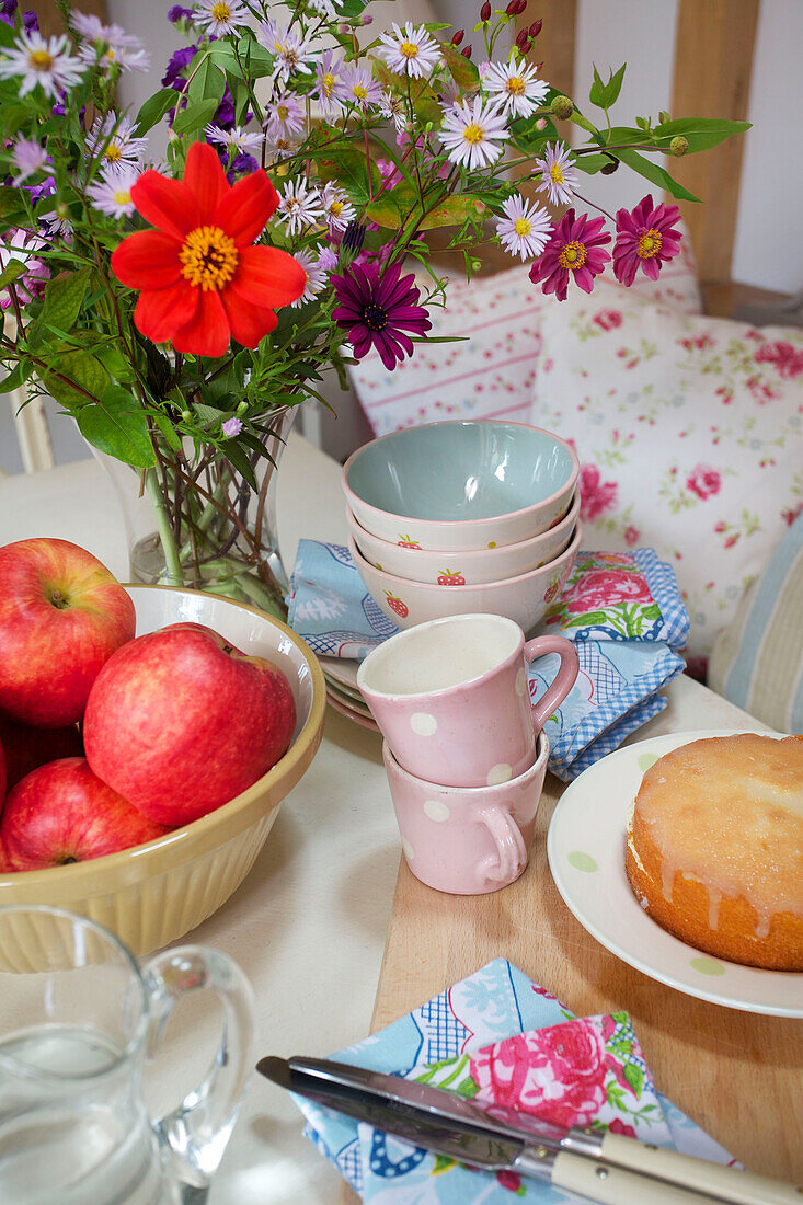 Schnittblumen, Äpfel und Kuchen auf einer Tischplatte mit Servietten in einem Cottage in Sandhurst, Kent, England, UK