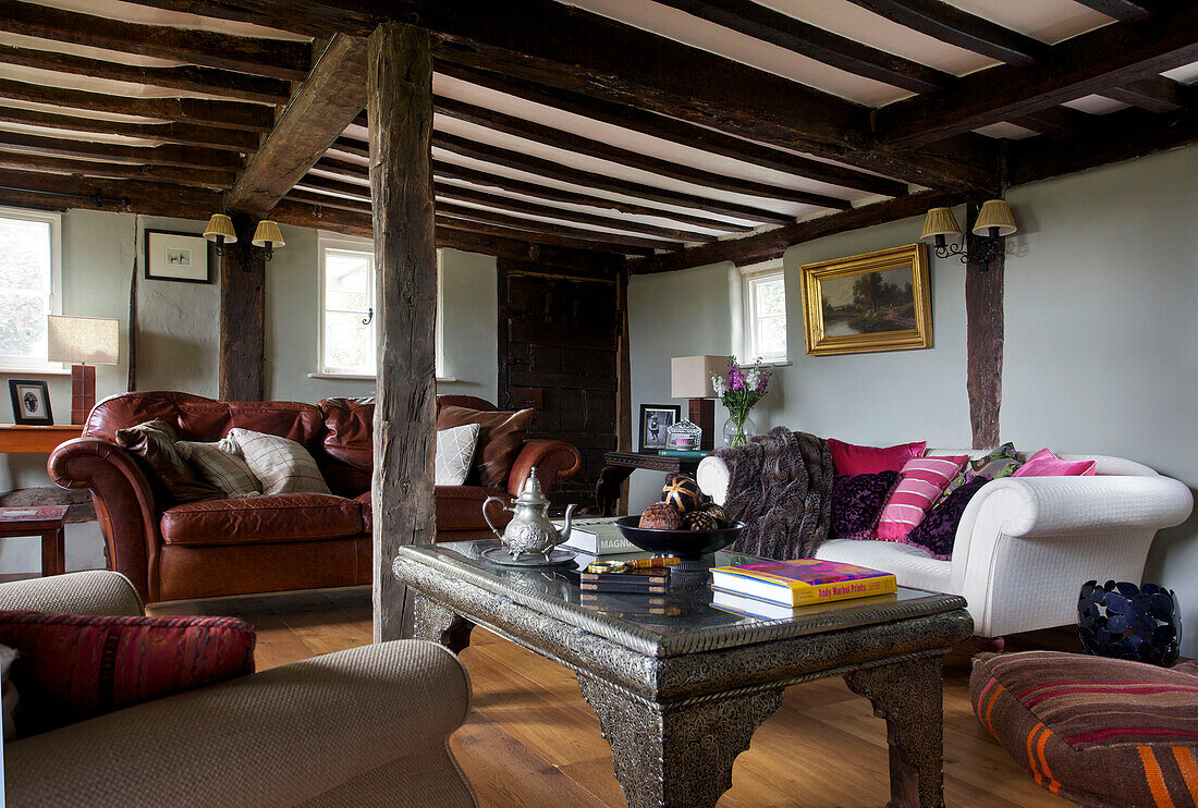 Braunes Ledersofa und Couchtisch aus Metall in einem Wohnzimmer mit Holzbalken in Sandhurst Cottage, Kent, England, UK