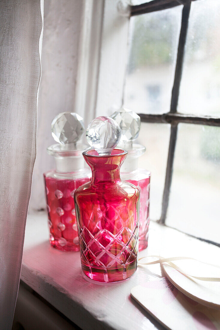Rosa handgefärbte Karaffen auf der Fensterbank von Egerton cottage, Kent, England, UK