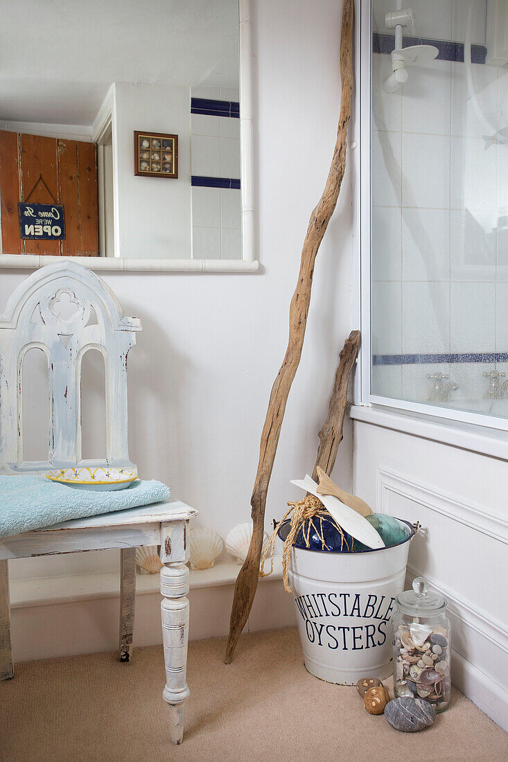 Seashells and driftwood with chair below bathroom mirror in Egerton cottage, Kent, England, UK