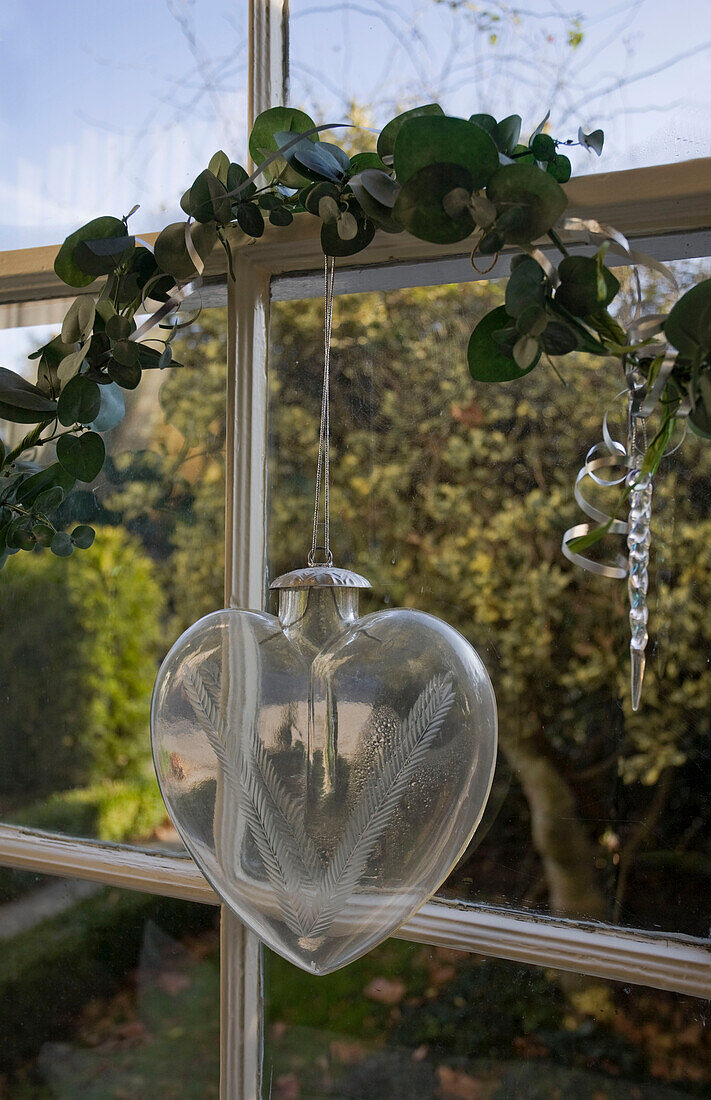Vintage-Glas-Weihnachtsschmuck und Blättergirlande im Fenster von Tenterden, Kent, England, UK