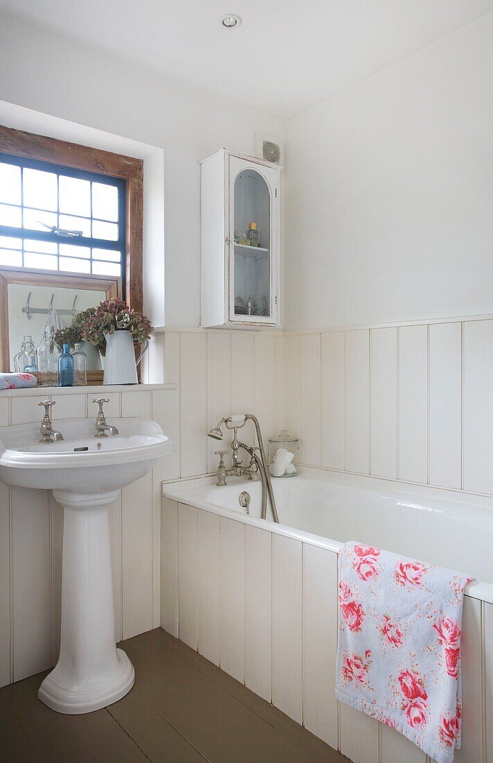 Geblümtes Handtuch mit Sockelbecken im weiß getäfelten Badezimmer eines Hauses in Cranbrook, Kent, England, UK