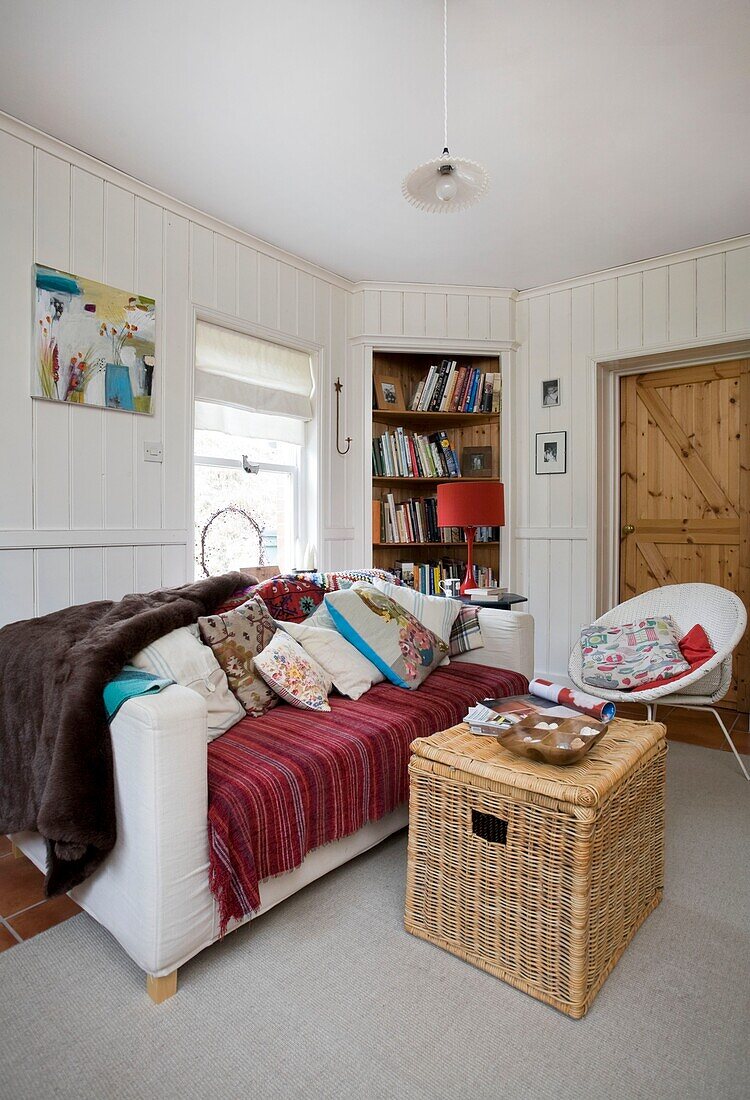 Sofa mit Korb und Eckbuchregal im Haus einer Familie in Tenterden, Kent, England, UK