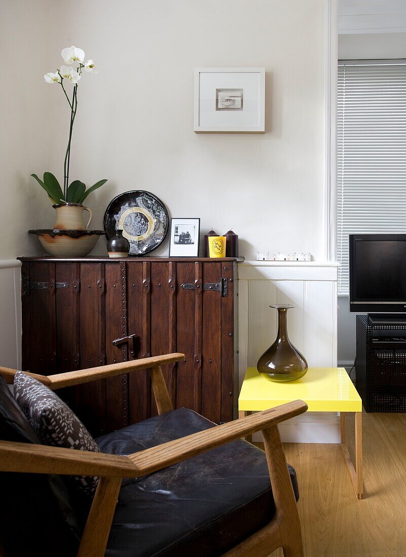 Schwarzer Ledersessel im dänischen Stil der 1940er Jahre im Wohnzimmer mit Orchidee auf dem Beistellschrank