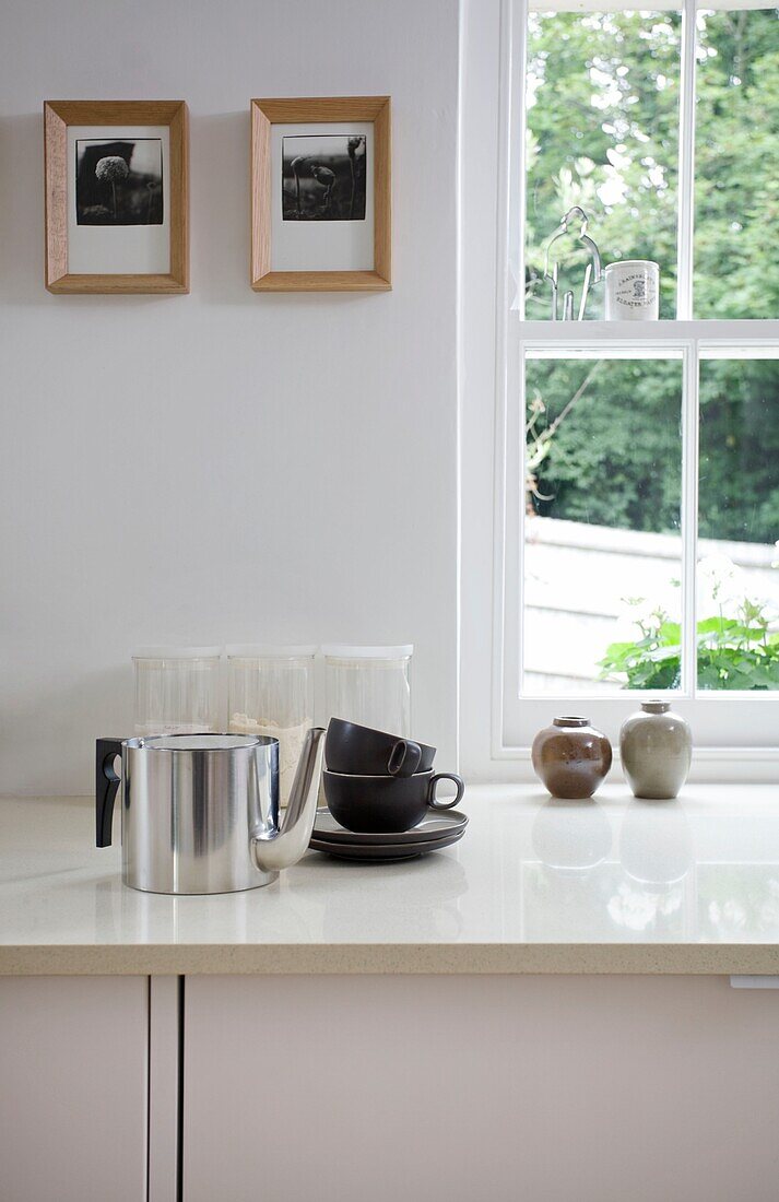 Metal teapot and cups on worktop at window in timber framed cottage