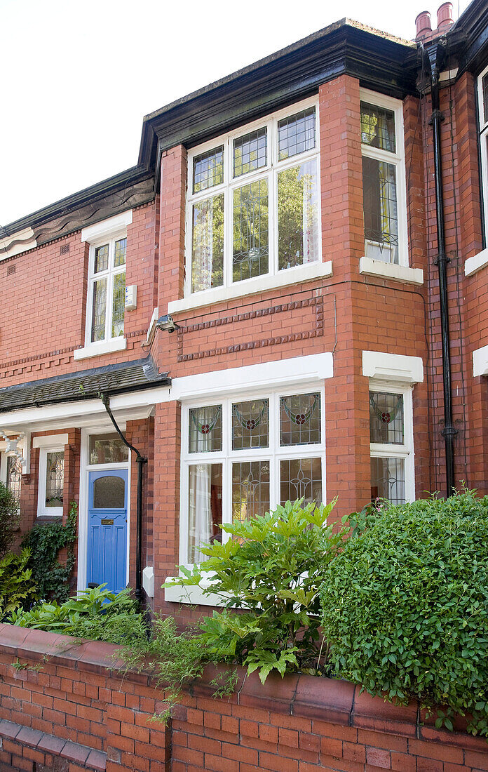 Brick terraced house with blue front door in Manchester, England, UK