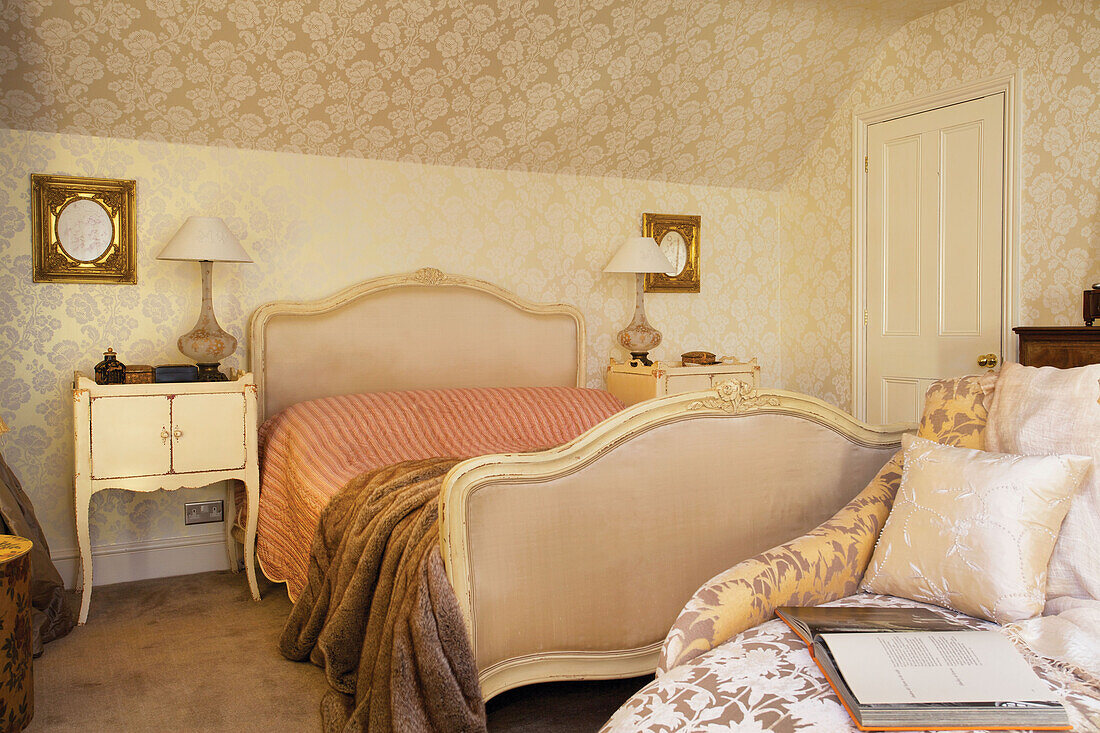 Pelzdecke auf einem Doppelbett in einem Raum mit gemusterter Tapete in einem Haus in Kent, England UK