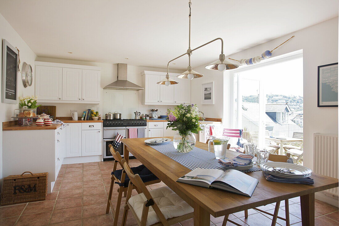 Wooden table in white fitted kitchen with tiled floor, Dartmouth, Devon, UK