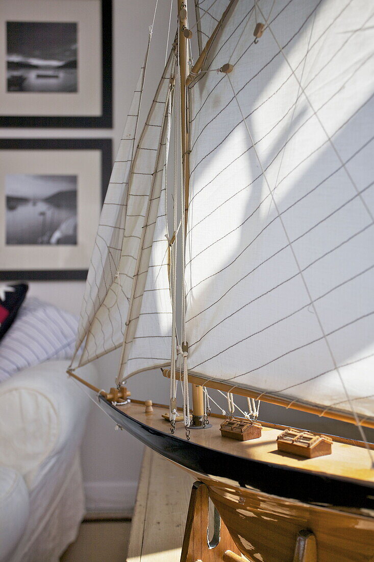 Sonnenlicht in den Segeln eines Modellboots im Wohnzimmer eines Hauses in Dartmouth, Devon, Großbritannien