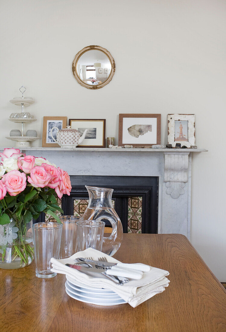 Gläser und Teller mit Rosen auf hölzernem Esstisch in Deal home Kent England UK