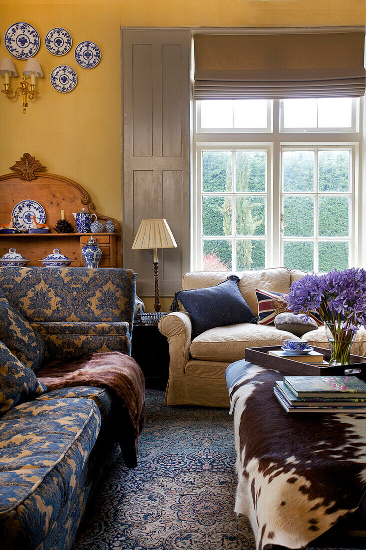 Cream and blue patterned sofas with ponyskin in Etchingham farmhouse living room East Sussex England UK