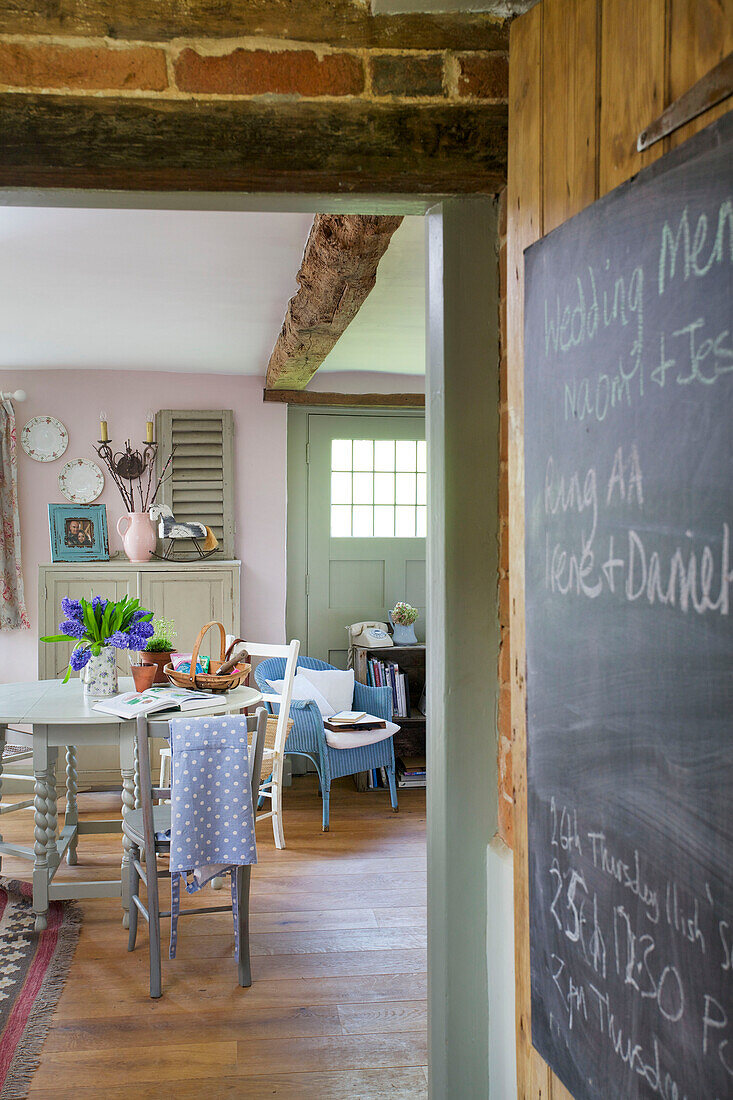 Blick durch die Tür mit Tafel zu Küchentisch und Stühlen in einem Bauernhaus in High Halden, Kent, England, UK