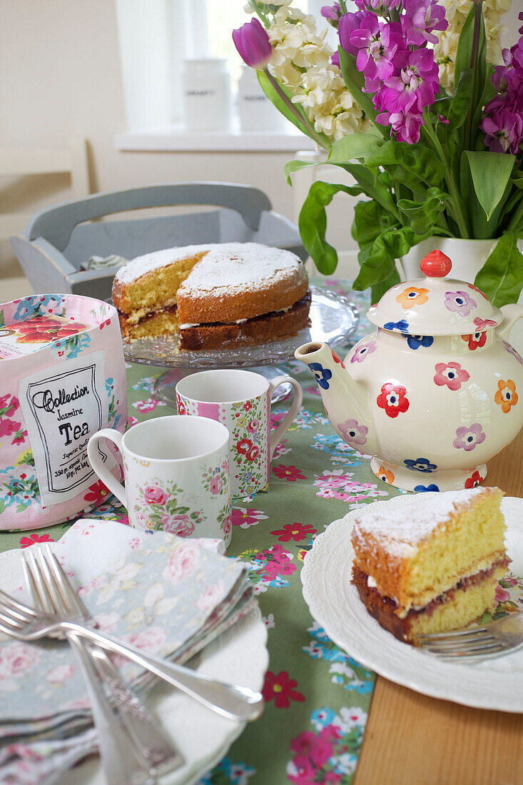 Victoria sponge cake and teapot on kitchen table in High Halden farmhouse Kent England UK