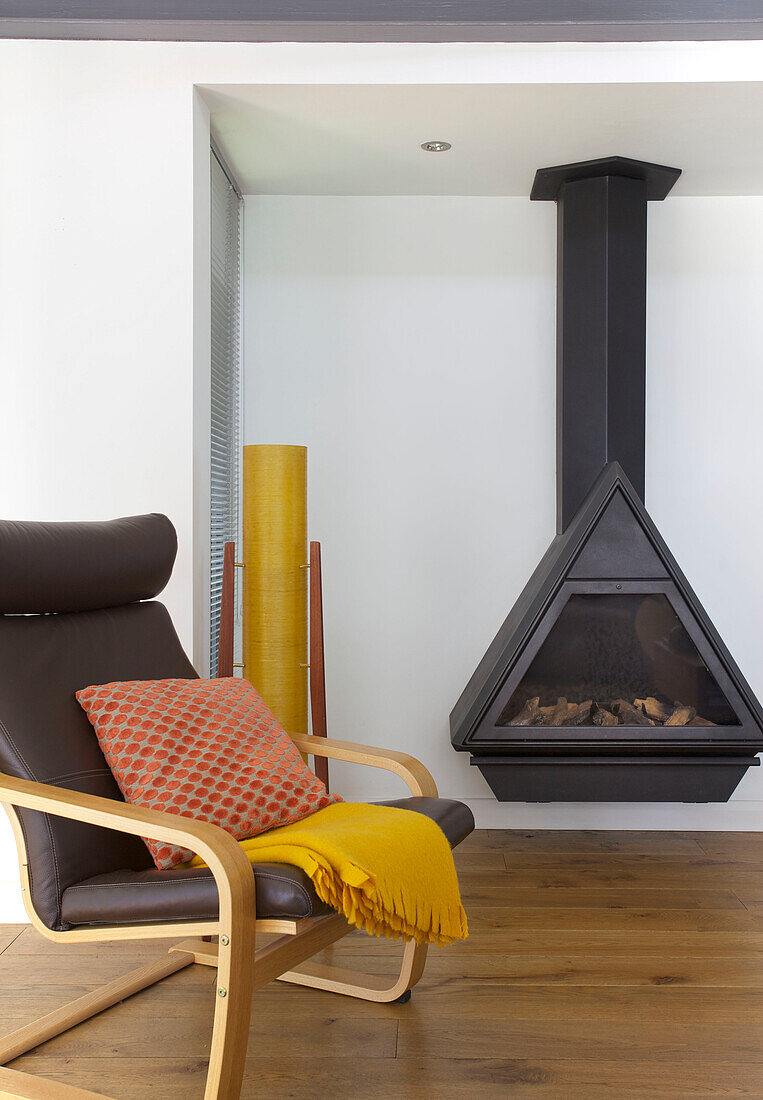 Brown leather armchair with wall-mounted woodburner in Rolvenden water tower conversion Cranbrook Kent England UK