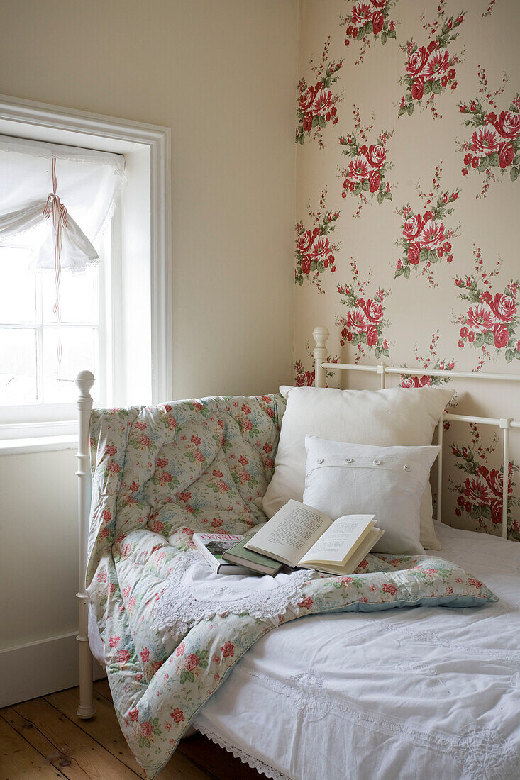 Floral patterned quilt and paper on day bed at window of Tenterden home, Kent, England, UK