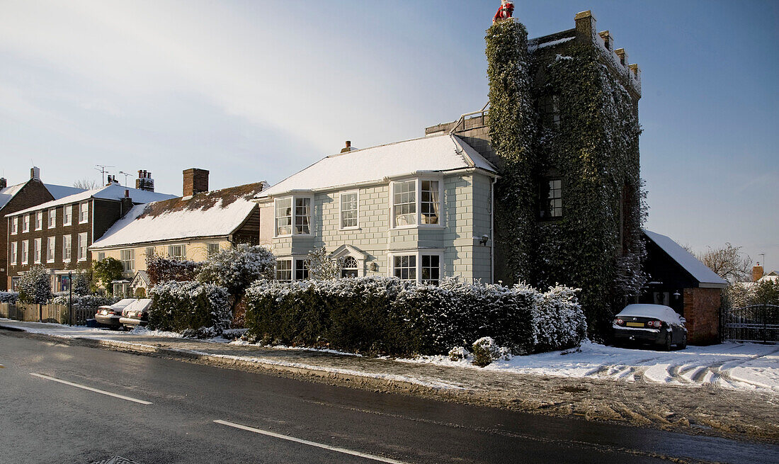 Painted home exterior with ivy clad tower and snowfall in Tenterden, Kent, England, UK