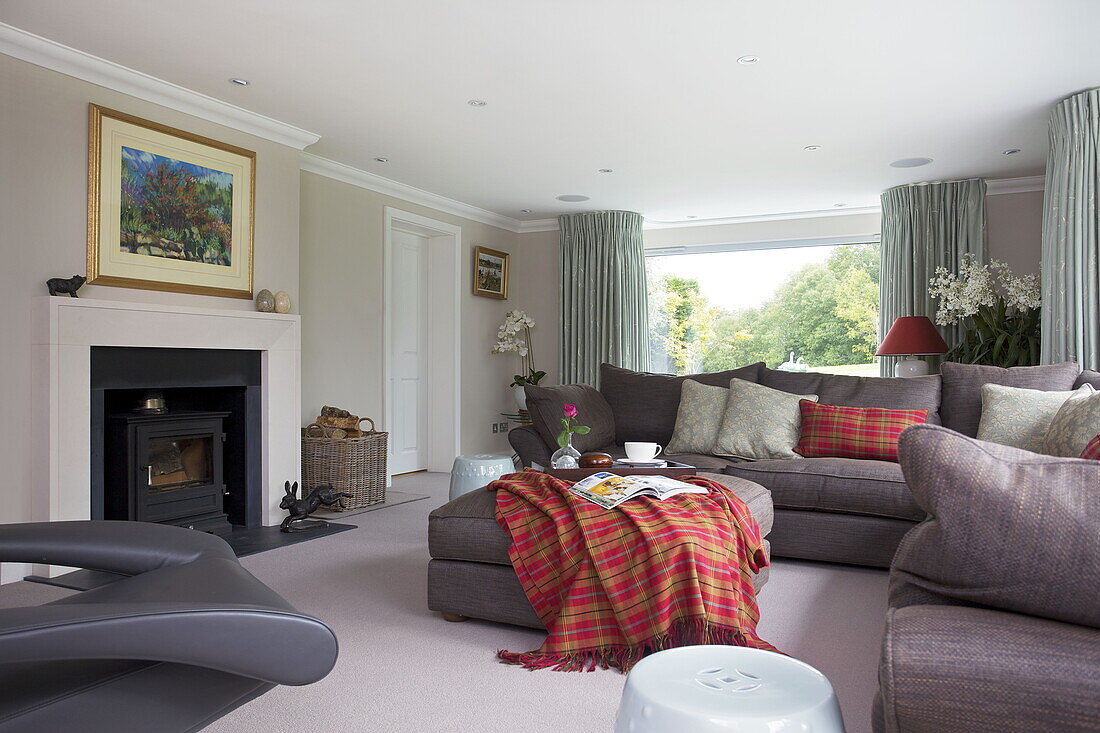 Bright tartan checked blanket on footstool in living room of contemporary farmhouse in Nuthurst, West Sussex, England, UK