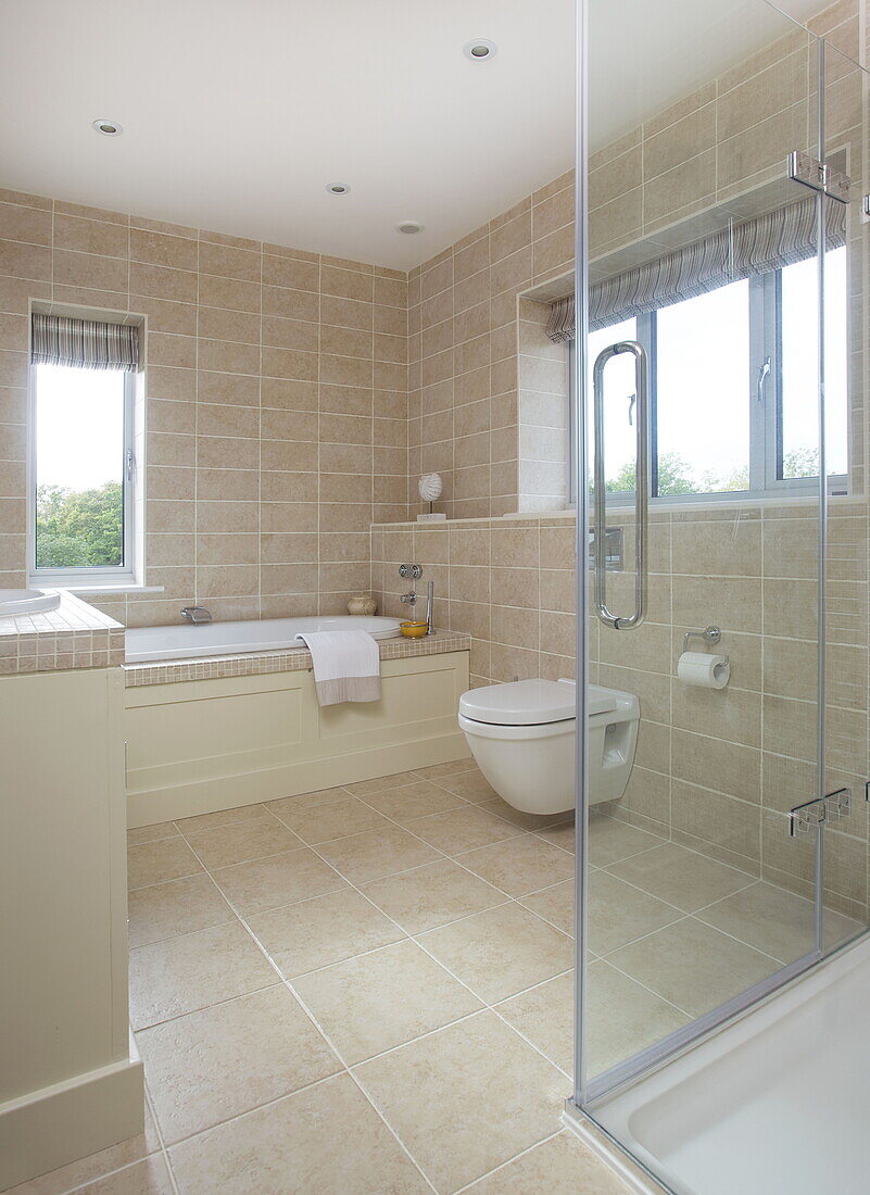 Neutral gefliestes Badezimmer in einem modernen Bauernhaus in Nuthurst, West Sussex, England, UK