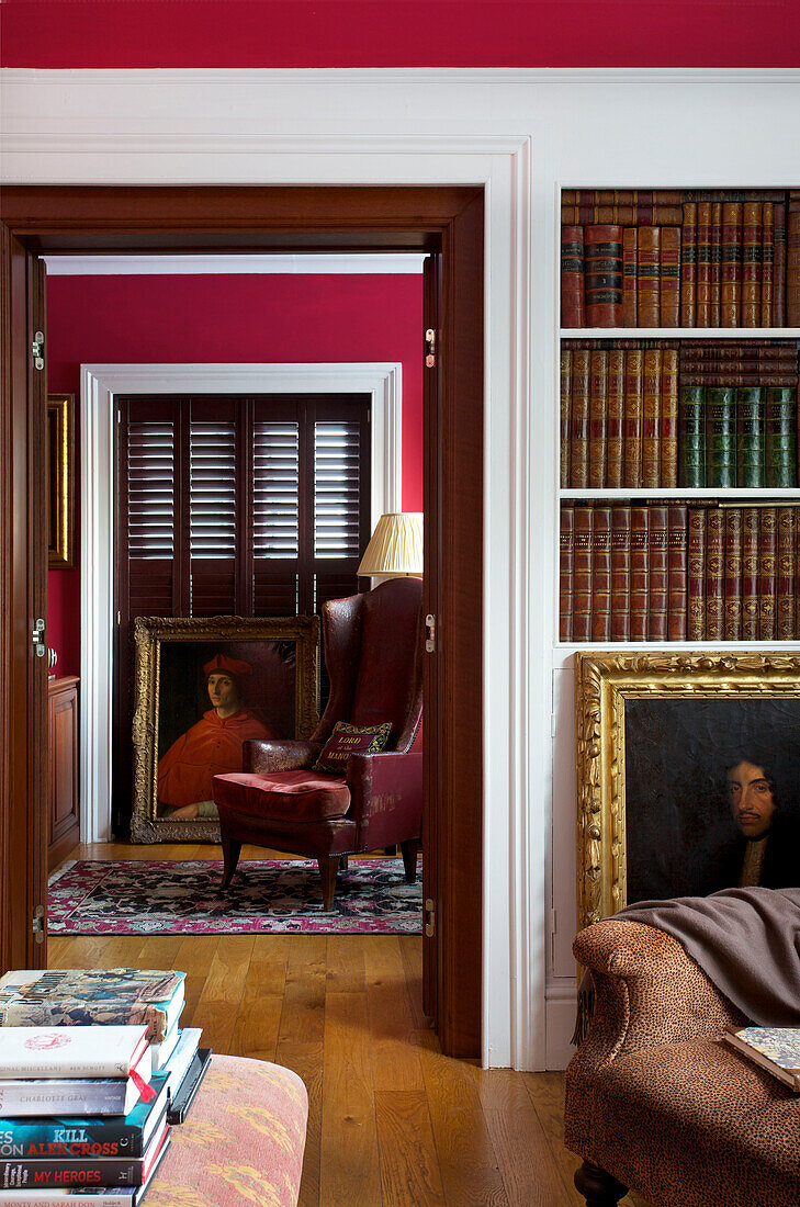 Blick durch die Tür von der Bibliothek mit gebundenen Büchern und goldgerahmtem Ölgemälde in einem Haus in Kent, England UK