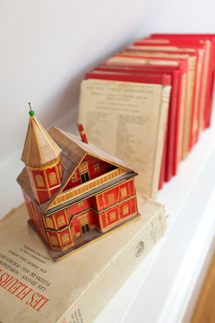 Hardbacked books and model house on shelf in Emsworth home Hampshire England UK