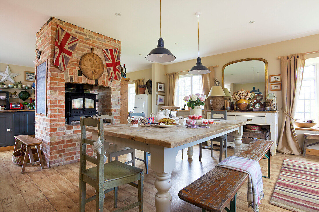 Offene Küche und Esszimmer mit Holzofen in freiliegender Backsteinwand in einem Haus in Kent, England, UK