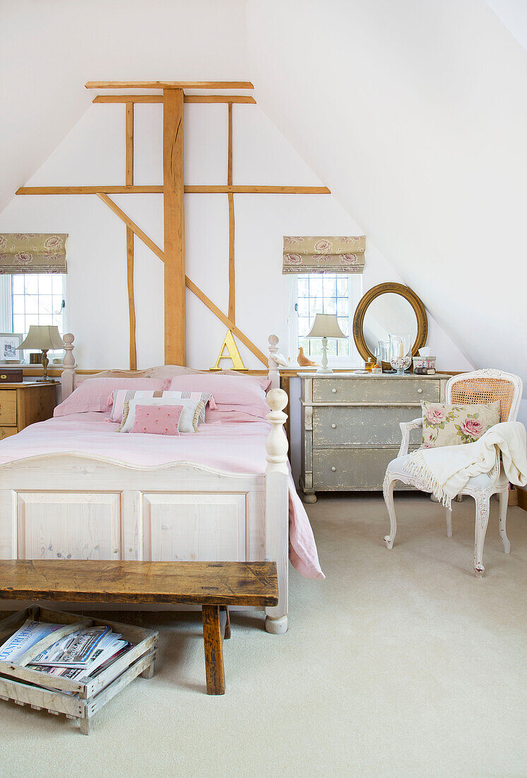 Rosa Bettdecke in einem Schlafzimmer mit Holzrahmen in einem Bauernhaus in Kent, England, UK