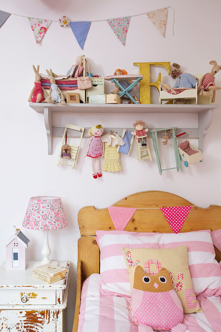 Kopfteil aus Holz mit Wimpeln und Kuscheltieren in einem Mädchenzimmer in einem Einfamilienhaus in Kent England UK