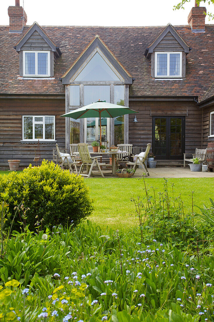 Sonnenschirm und Gartenmöbel an der Außenseite eines Hauses in Kent mit Dachgaube England UK