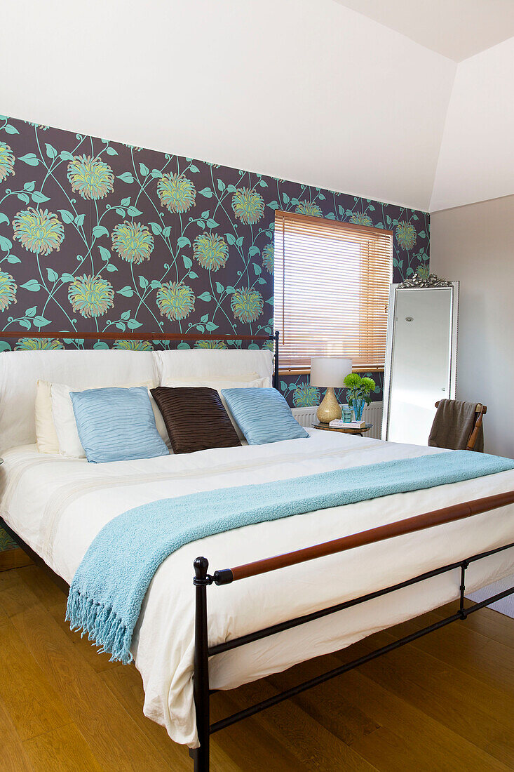 Double bed with floral patterned wallpaper in Hayling Island beach house Hampshire England UK