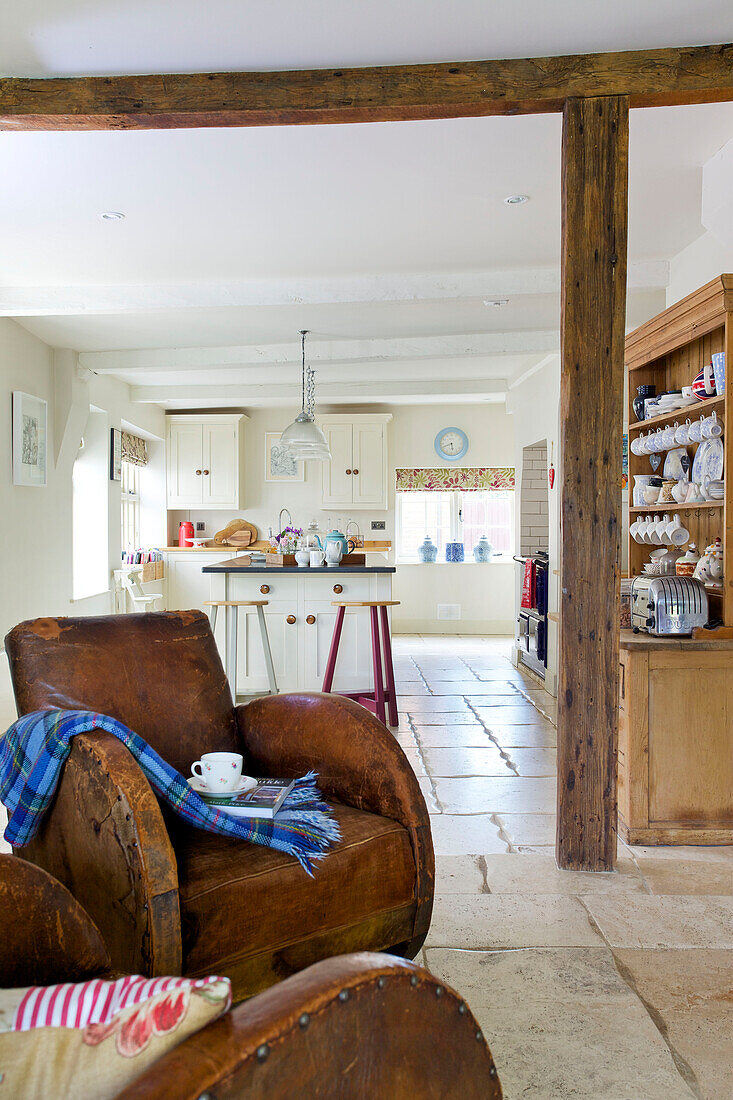 Ein Paar passender brauner Ledersessel mit Blick auf eine offene Küche in einem Haus in Bishops Sutton, Alresford, Hampshire, England UK
