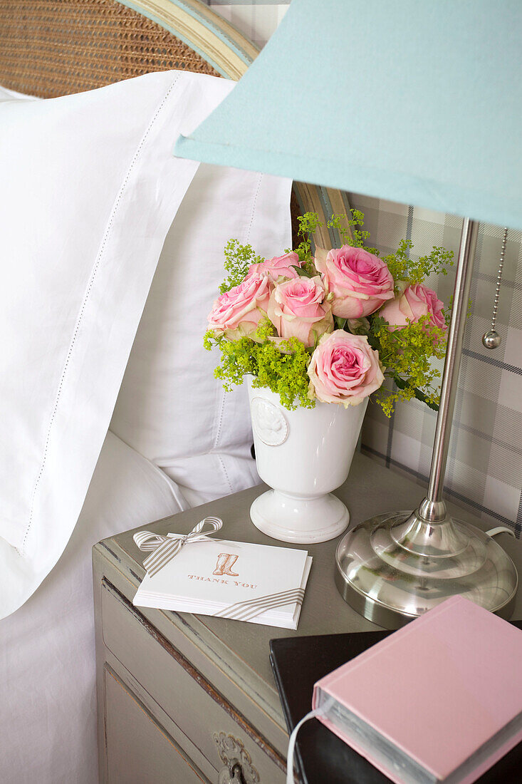 Pink roses and diary with bedside lamp in Kilndown home Cranbrook Kent England UK