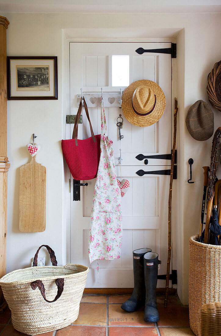 Hats and apron with wellington boots on back of door in Worth Matravers cottage Dorset England UK