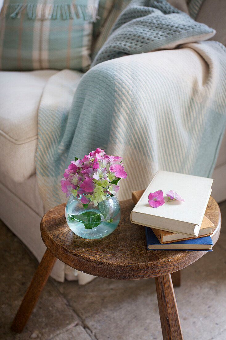 Schnittblumen und Bücher auf Beistelltisch mit Sofa in Worth Matravers cottage Dorset England UK