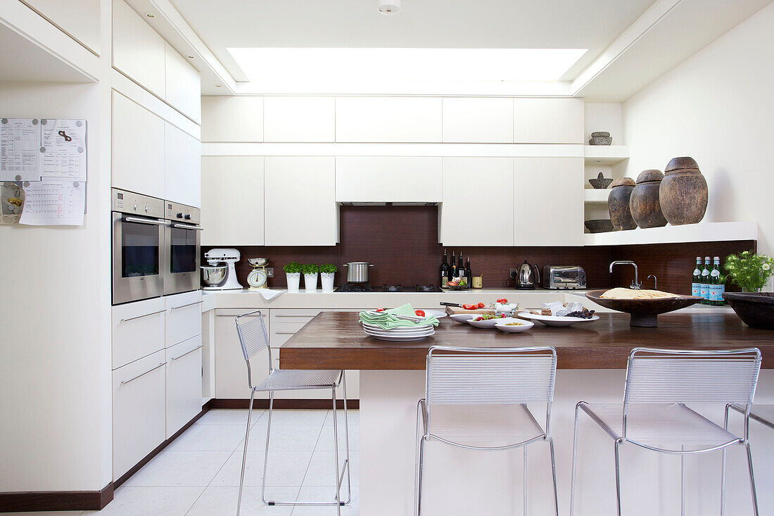 Chrome chairs at table in white fitted kitchen in Wandsworth home London England UK