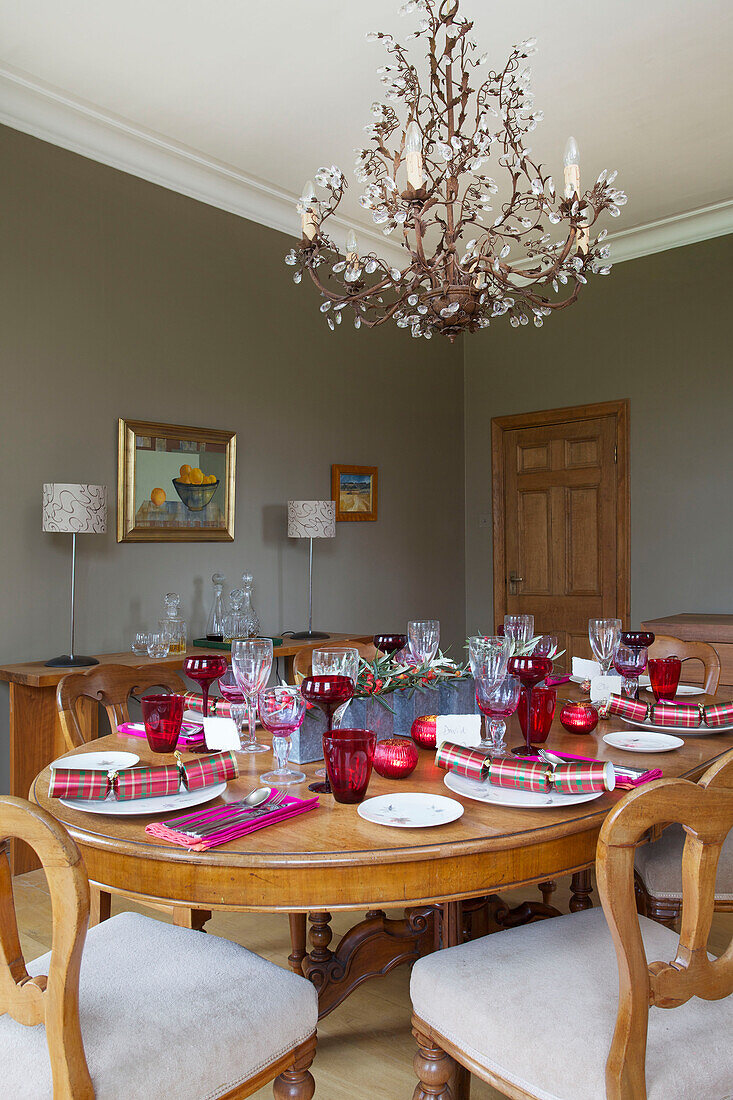 Christmas crackers and wineglasses on wooden dining table with chandelier in Faversham home Kent England UK