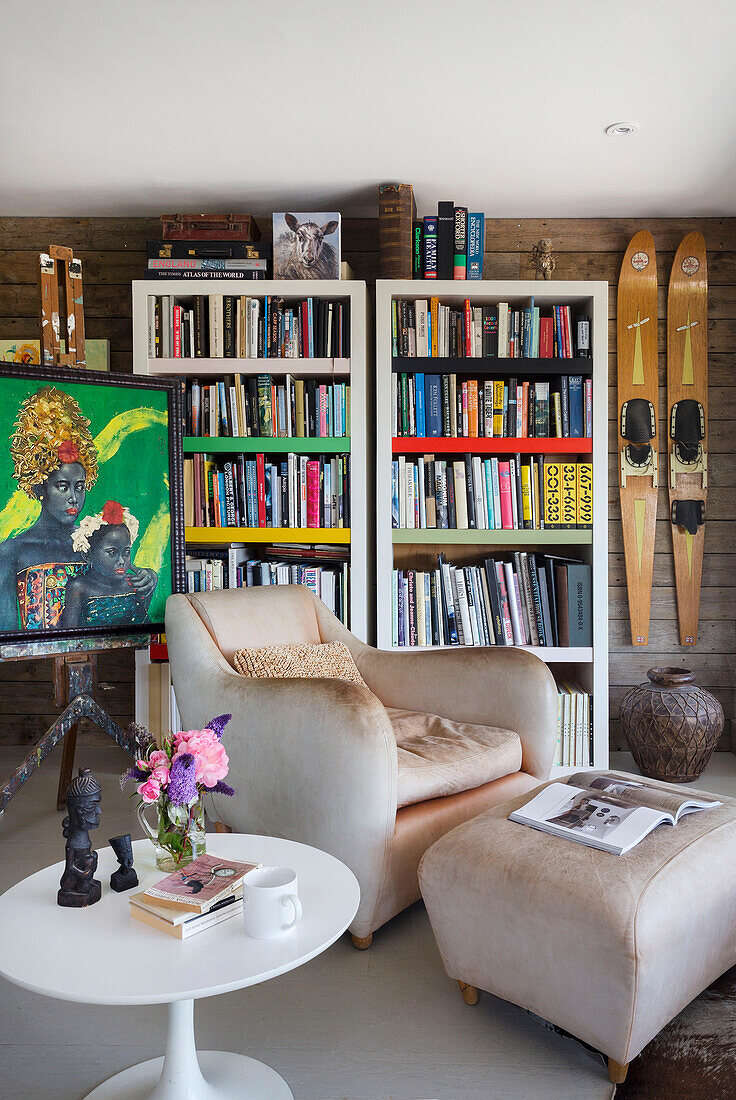 Sessel und Fußhocker mit Bücherregal und Kunstwerken auf Staffelei in Rye East Sussex UK