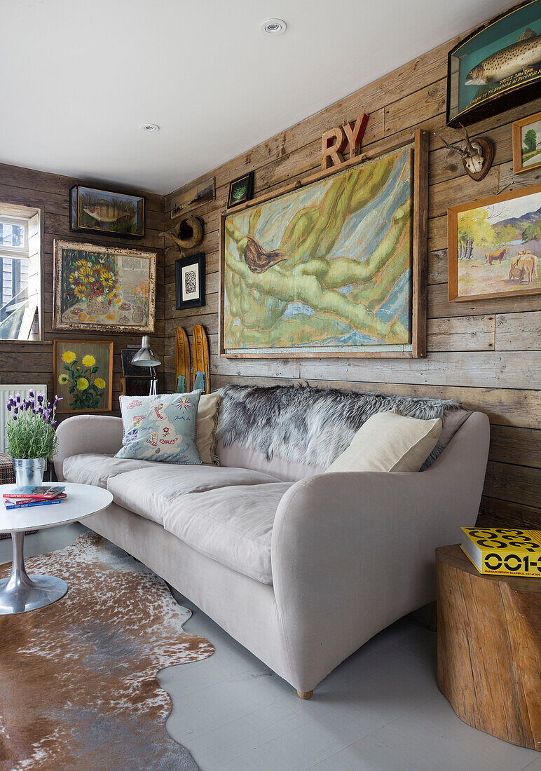 Gerahmtes Kunstwerk und Holzverkleidung mit cremefarbenem Sofa in einem Haus in Rye, East Sussex, Großbritannien