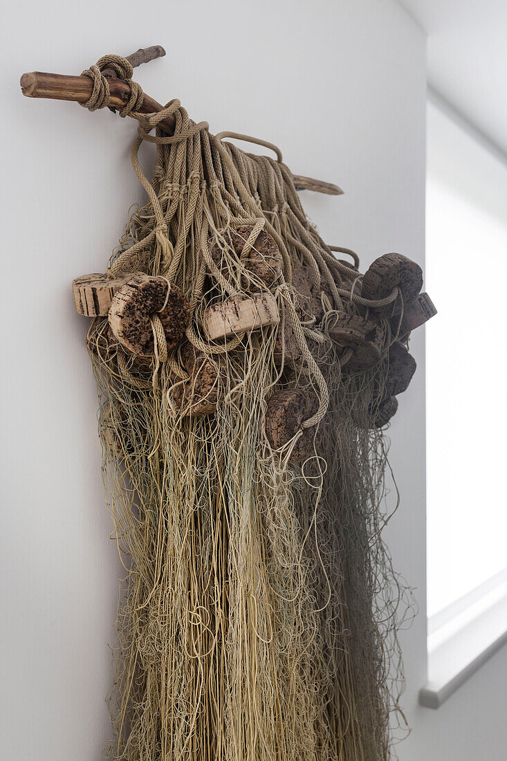 Altes Fischernetz und Bojen von Hand auf Treibholz in einem Haus in Rye, East Sussex UK