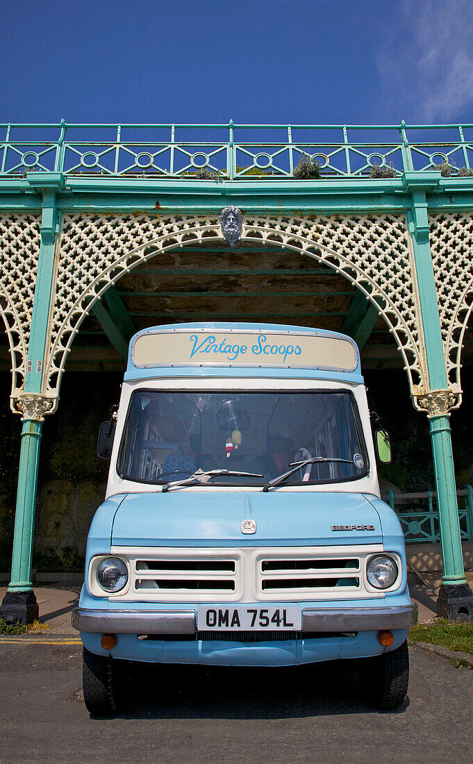 Light blue ice cream van parked under wrought iron promenade in Brighton Sussex England UK