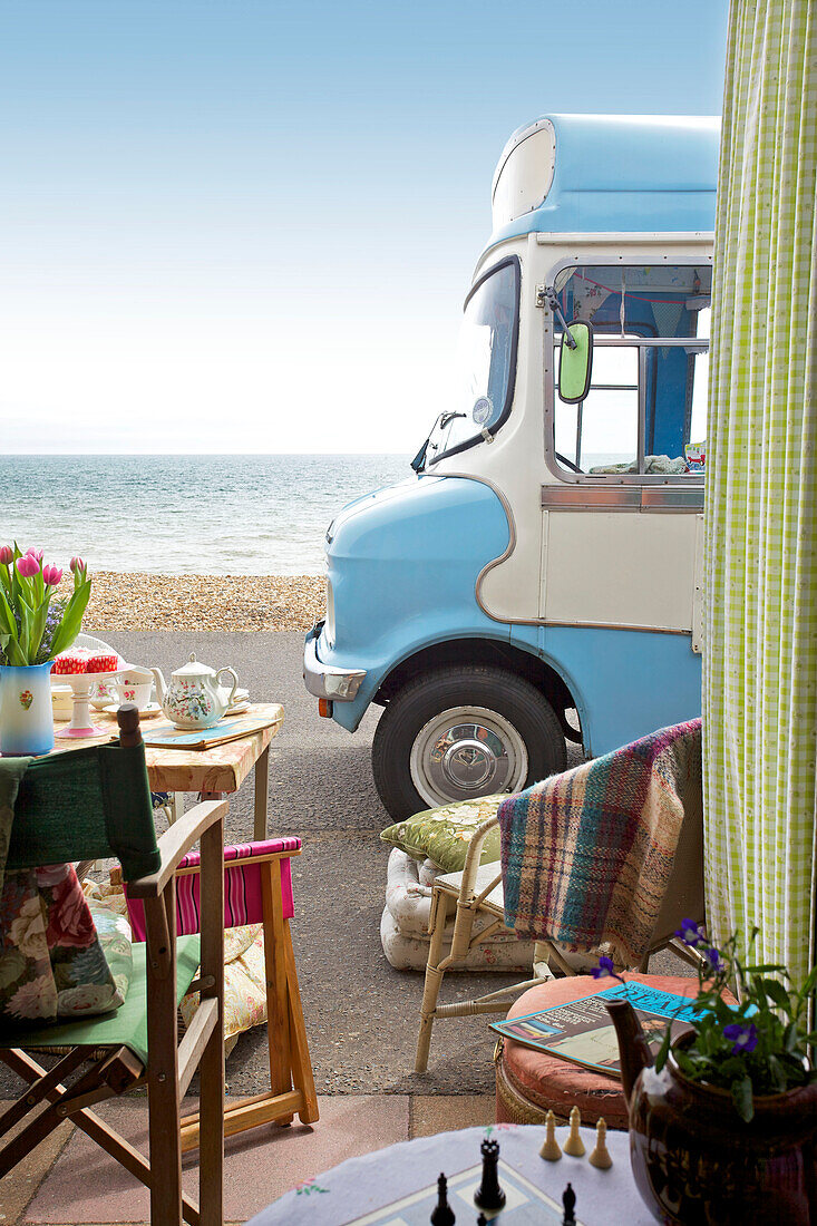 View through doorway with table and chairs to ice cream van parked on Brighton promenade Sussex England UK
