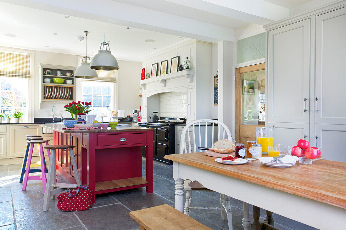 Hellrosa Kücheninsel mit Fliesenboden und Tisch in einem Haus in Woodchurch, Kent, England, Vereinigtes Königreich