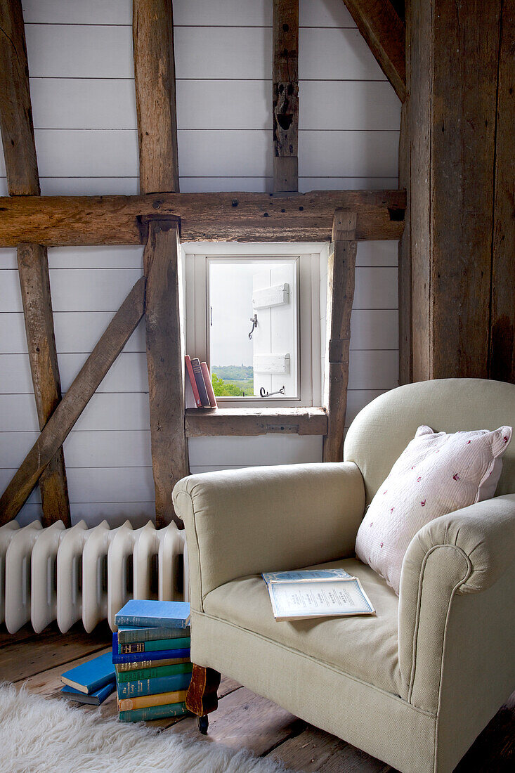Armchair at original latched window in Grade ll listed windmill conversion Kent UK