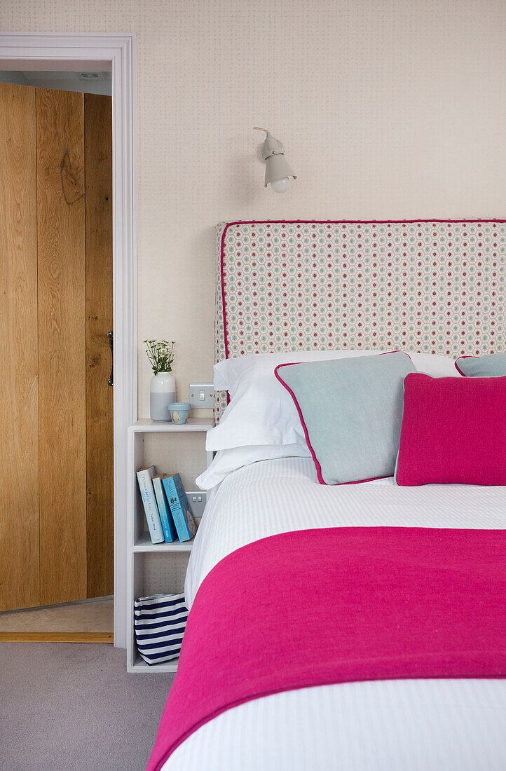 Bright pink blanket and spotted headboard with bedside shelves in Dartmouth Devon UK