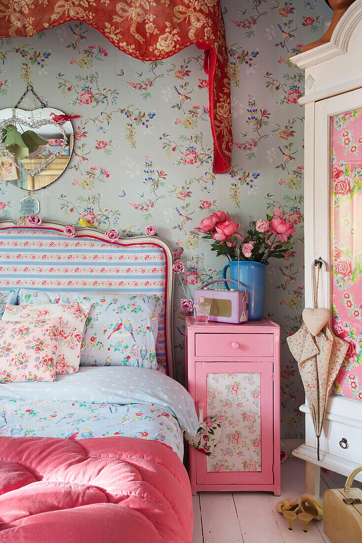 Kontrastierende Blumenmuster mit upgecycelten Möbeln in einem Schlafzimmer in Tenterden, Kent, Großbritannien