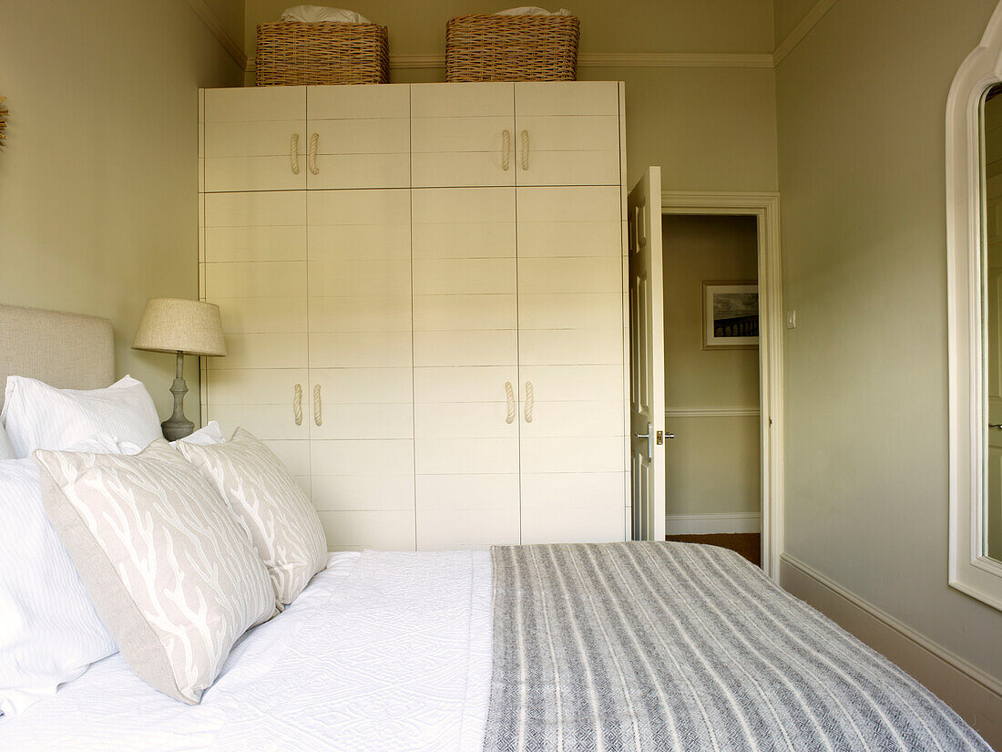 Gestreifte Decke auf dem Bett mit weißem Schrank im Schlafzimmer eines Hauses in Kensington London England UK