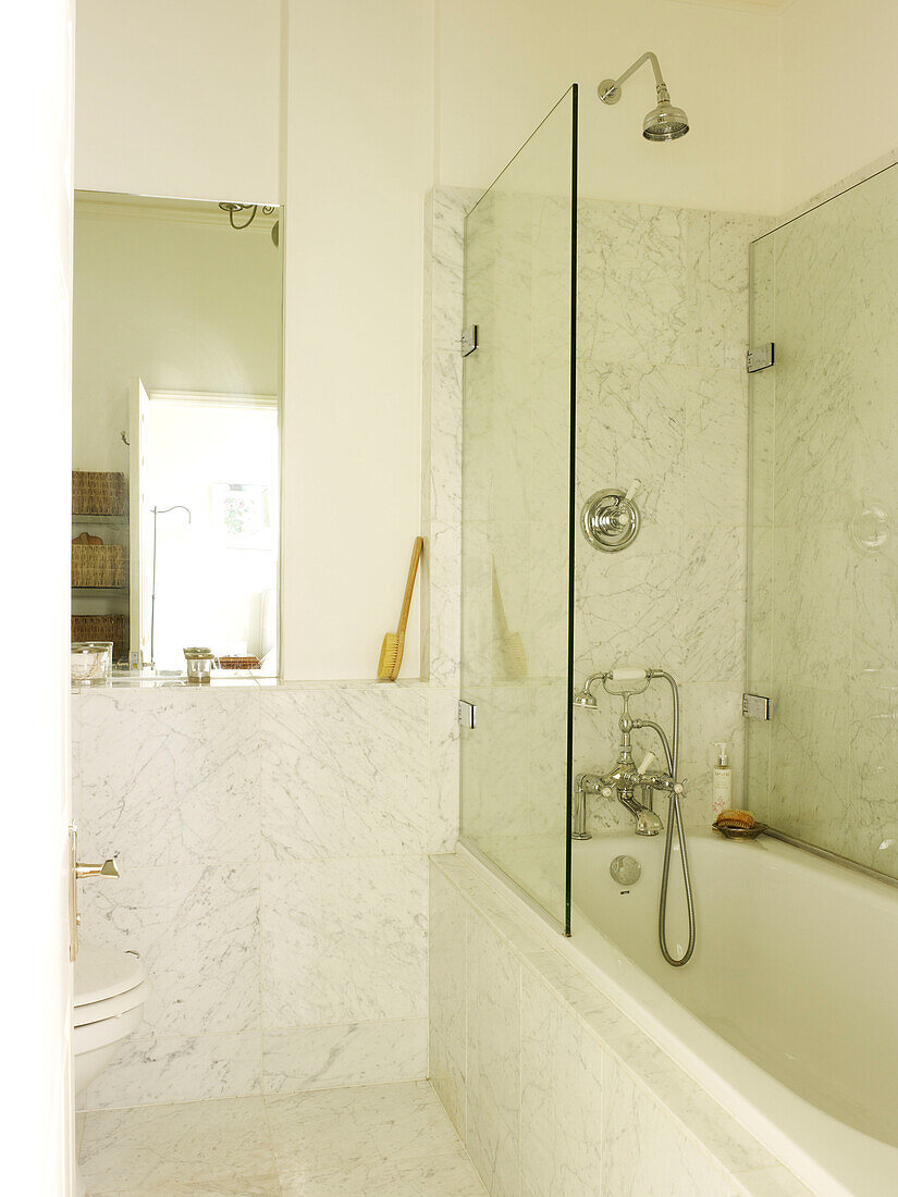 Duschabtrennung an der Badewanne in einem Marmorbad in einem Haus in Kensington, London, England, UK