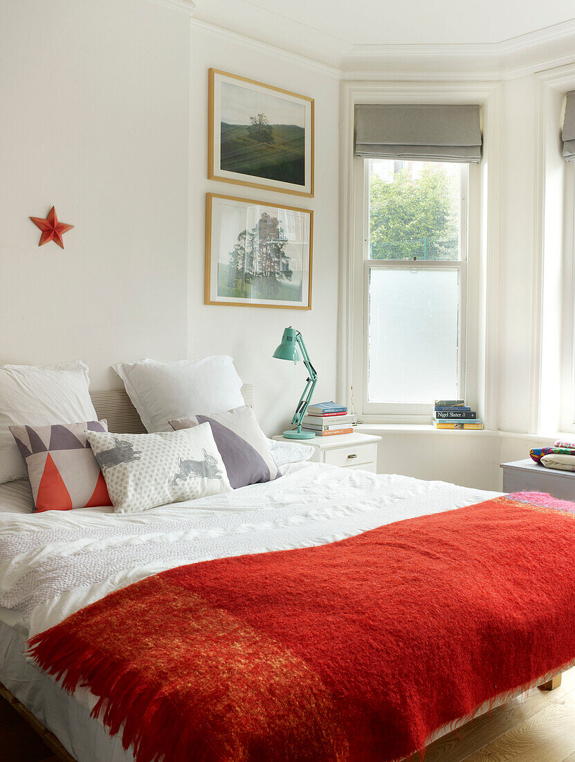 Rote Decke auf einem Doppelbett in einem Zimmer mit Erkerfenster in London, England, UK