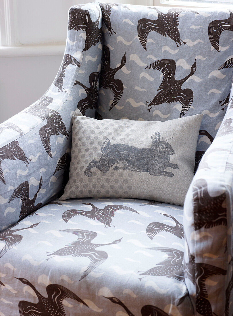 Bird motif upholstered armchair with cushion in London home England UK