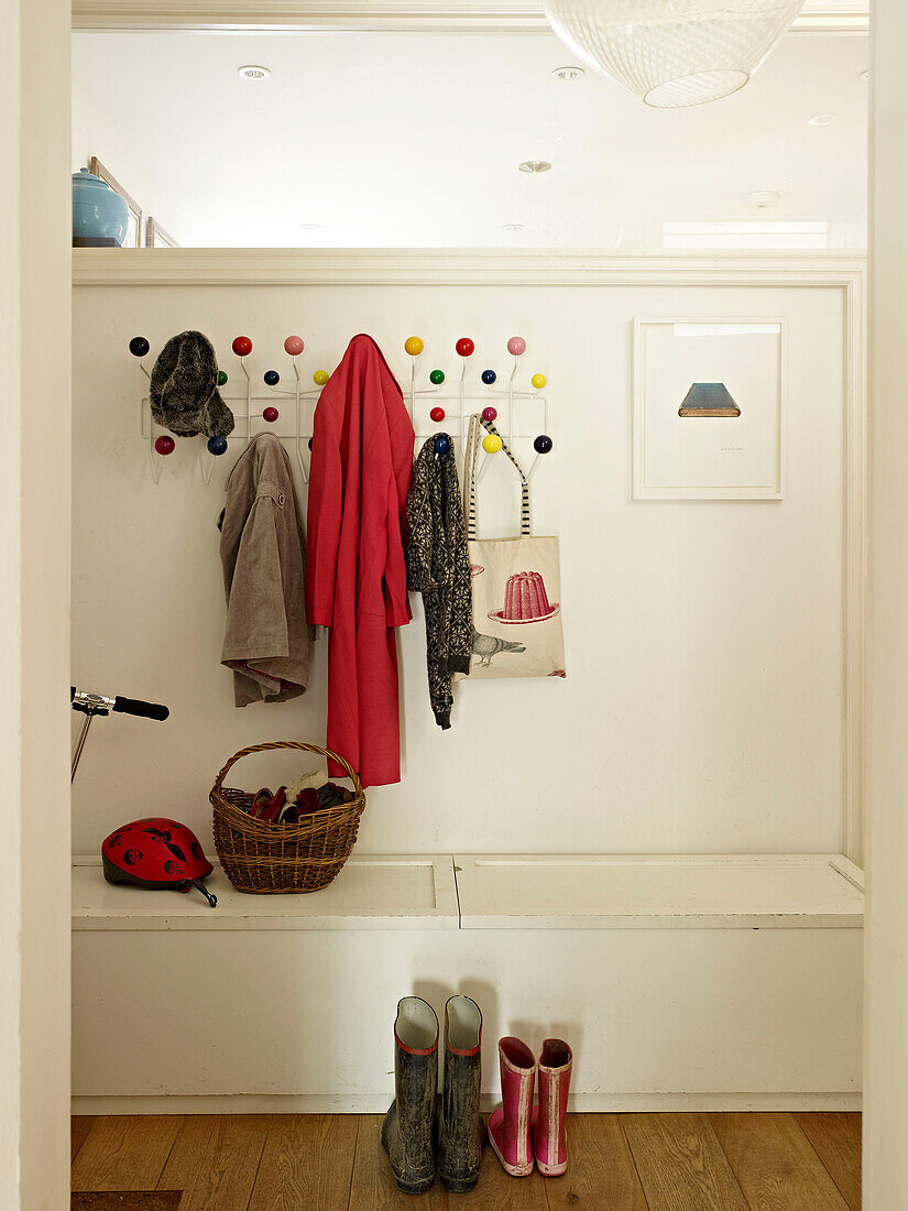 Coats and hats hanging in hallway of London home with wellington boots England UK