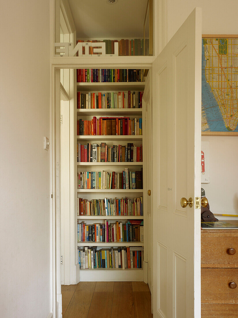 Bookshelf viewed through bedroom doorway in London home England UK